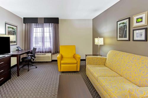 a hotel room with a couch and a desk and a computer at La Quinta by Wyndham Milwaukee Delafield in Delafield