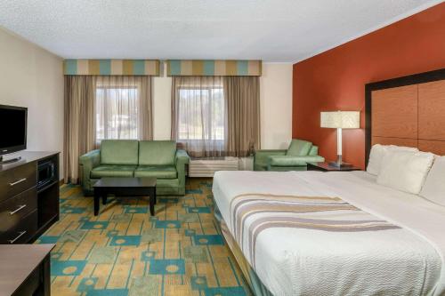 a hotel room with a bed and chairs and a television at La Quinta by Wyndham Meridian in Meridian