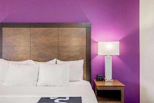a hotel room with a bed and a purple wall at La Quinta by Wyndham Baltimore BWI Airport in Linthicum Heights