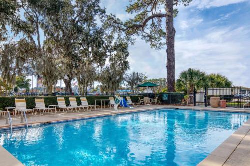 a swimming pool with chairs and tables and trees at La Quinta by Wyndham Savannah Southside in Savannah