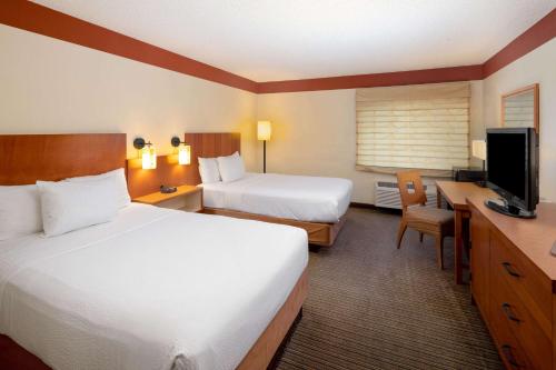 a hotel room with two beds and a flat screen tv at La Quinta by Wyndham Savannah Southside in Savannah