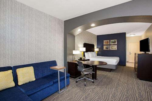 a hotel room with a bed and a blue couch at La Quinta by Wyndham Palestine in Palestine