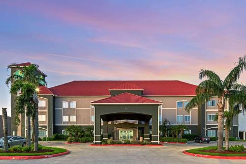 a hotel with palm trees in a parking lot at La Quinta by Wyndham Mercedes in Mercedes