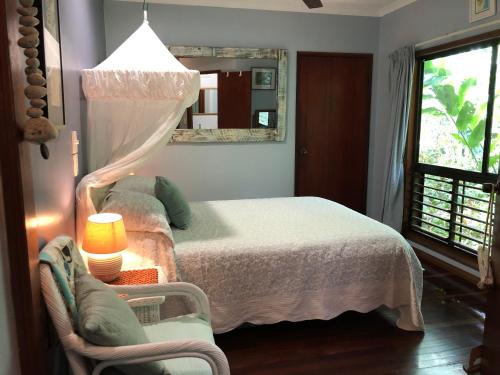 a bedroom with a bed and a chair and a mirror at Mossman Gorge Bed and Breakfast in Mossman