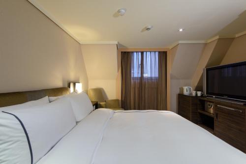 a hotel room with a large bed and a flat screen tv at K Hotel Taipei in Taipei