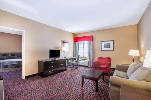 a hotel room with a couch and a desk with a television at La Quinta by Wyndham Conway in Conway