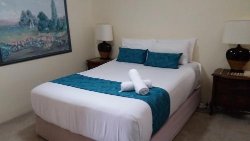 a bedroom with a large white bed with blue pillows at Beaconlea in Gold Coast