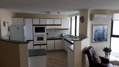 a small kitchen with white cabinets and appliances at Beaconlea in Gold Coast