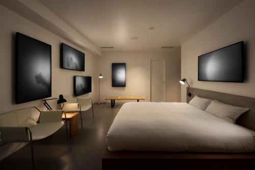 a bedroom with a large white bed and chairs at BnA Alter Museum in Kyoto