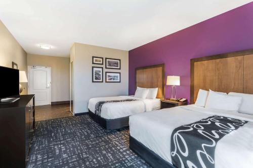 a hotel room with two beds and a flat screen tv at La Quinta by Wyndham Monahans in Monahans