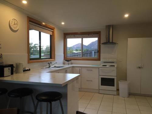 a kitchen with a counter top and two windows at Gumnut Cottage in Coles Bay