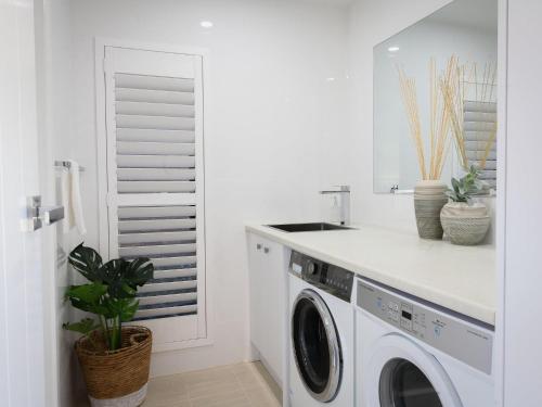 a white laundry room with a washer and dryer at Spirit of Gerroa in Gerroa
