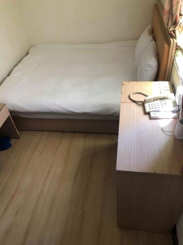 Huaxin Hotel في جينتشينغ: غرفة نوم مع سرير ومكتب مع هاتف