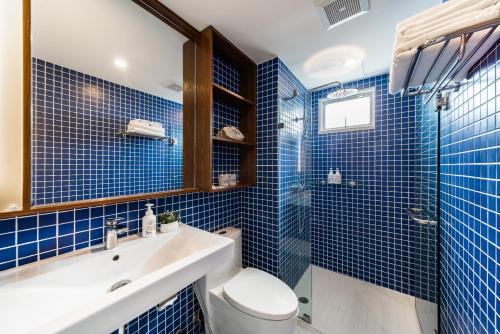 a blue tiled bathroom with a toilet and a sink at Hotel Amber Sukhumvit 85 in Bangkok