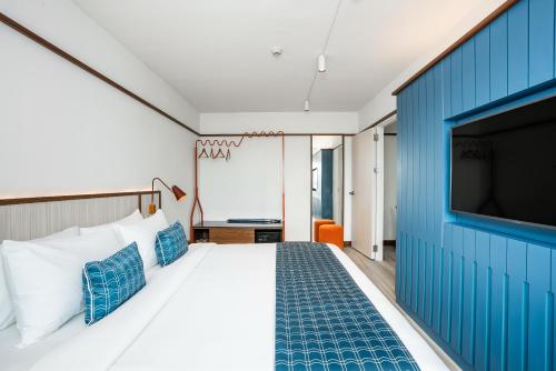 a hotel room with a large bed with a blue wall at Hotel Amber Sukhumvit 85 in Bangkok