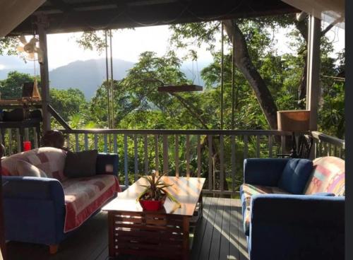 a porch with two couches and a table on a deck at Mossman Gorge Bed and Breakfast in Mossman