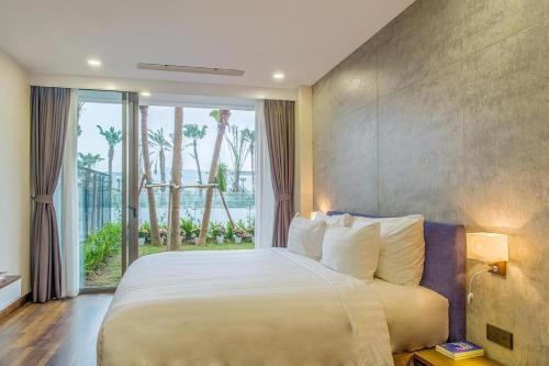 una camera da letto con un letto grande e una grande finestra di Flamingo Dai Lai Resort - by BAY LUXURY a Yen