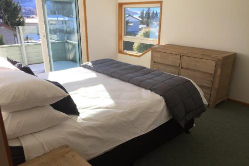 a bedroom with a bed and a dresser and a window at Smithy's in Lake Tekapo