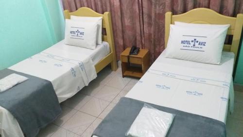 two beds in a hotel room with avertisement for at Hotel Cruz de Aviz in Sao Paulo