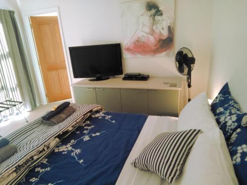 a bedroom with a bed and a flat screen tv at Golden Caves - Bed and Breakfast in Takaka