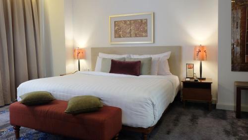 a bedroom with a large white bed and a red stool at Jambuluwuk Malioboro Hotel Yogyakarta in Yogyakarta