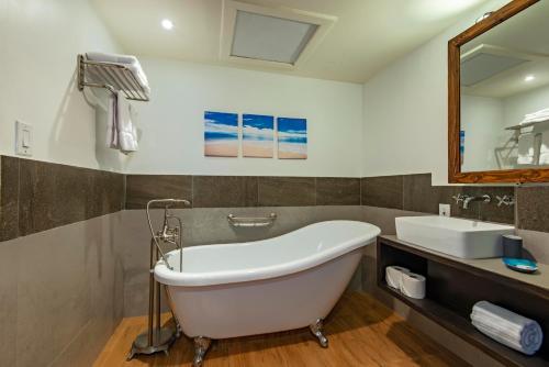 a bathroom with a tub and a sink and a mirror at Palau Central Hotel in Koror