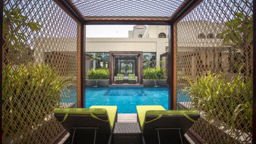 a swimming pool with two yellow chairs in front of a fence at InterContinental Dhaka by IHG in Dhaka