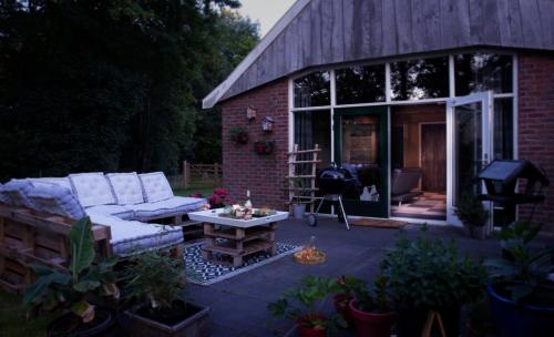 a patio with a couch and a table in front of a building at Buitenverblijf Het Grootenhuis in Winterswijk Henxel
