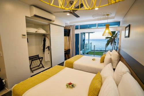 two beds in a room with a view of the ocean at Taumeasina Island Resort in Apia