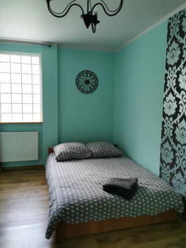 - une chambre avec un lit et un mur bleu dans l'établissement Pensjonat Dwa Dęby, à Hajnówka