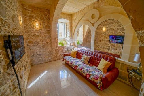 a living room with a red couch in a stone wall at Sant Anton tal-Qabbieza Farmhouse in Kerċem