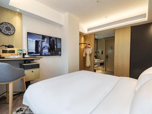 a hotel room with a bed and a tv at Paco Hotel BeiJing Road Metro Guangzhou-Free Shuttle Bus For Canton Fair in Guangzhou