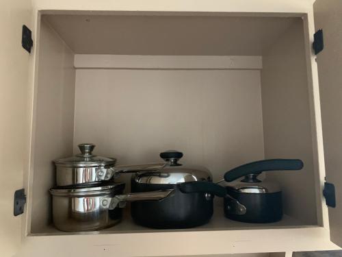 a shelf with pots and pans in a cabinet at Private Chalan Pago Apartment in Hagatna