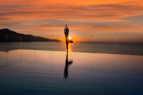 a statue of a woman standing in the water at sunset at Canvas Danang Beach Hotel in Da Nang