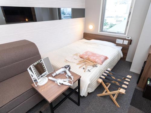 a hotel room with a bed and a table with a table at Super Hotel Beppu Ekimae in Beppu