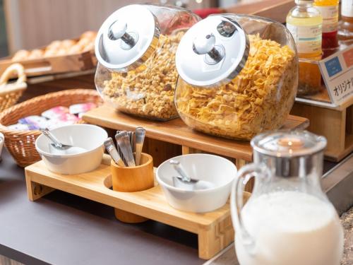 a counter with some bowls and plates and milk at Super Hotel Beppu Ekimae in Beppu