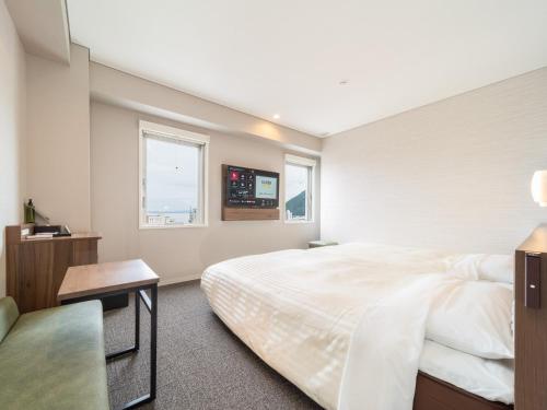 a bedroom with a large white bed and a window at Super Hotel Beppu Ekimae in Beppu
