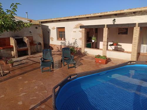 un patio trasero con piscina y sillas y una casa en Casa La Tora, en Deltebre