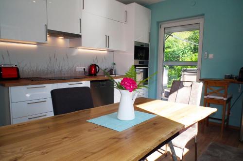 a kitchen with a table with a vase of flowers on it at Baker's Pond Apartment Two in Velden am Wörthersee