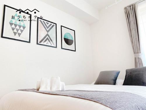 a bedroom with a bed and pictures on the wall at OUCHI HOTEL Miyajimaguchi in Hatsukaichi
