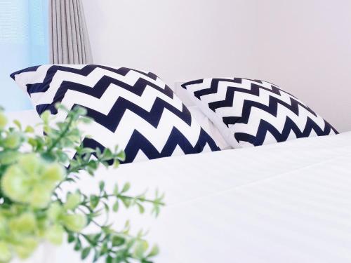 two black and white pillows on a bed at OUCHI HOTEL Miyajimaguchi in Hatsukaichi