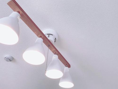 a light fixture with four lights on a ceiling at OUCHI HOTEL Miyajimaguchi in Hatsukaichi