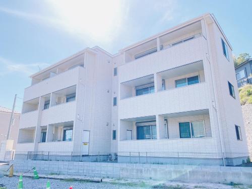 an apartment building with a white facade at OUCHI HOTEL Miyajimaguchi in Hatsukaichi