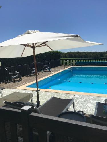 - un parasol blanc à côté de la piscine dans l'établissement Maison L’allee, à Lézignac-Durand