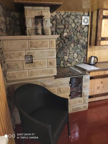 eine Küche mit einer Steinmauer und einem schwarzen Stuhl in der Unterkunft Чан-садиба Гуцульська пісня in Mykulytschyn