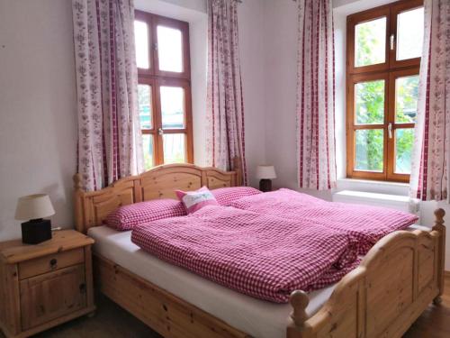 a bedroom with a wooden bed with pink sheets and windows at Ferienappartment zum grünen Hirsch in Bad Ischl