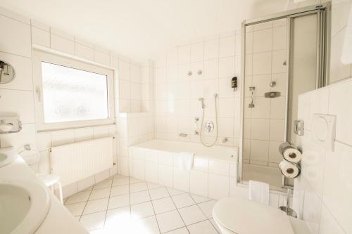 a white bathroom with a shower and a sink at Hotel Traube Rüdesheim in Rüdesheim am Rhein