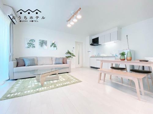 a white living room with a couch and a table at OUCHI HOTEL Miyajimaguchi in Hatsukaichi