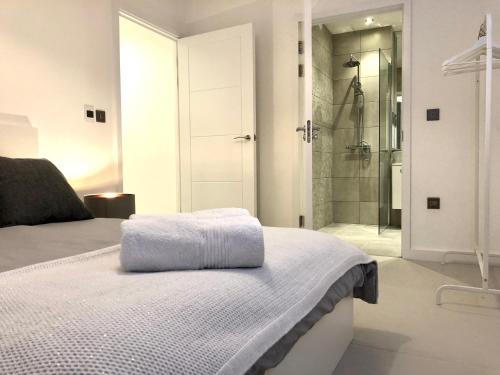 a white bedroom with a shower and a bed at Panoramic Park And City Penthouses Retreat in London