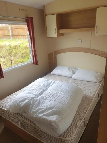 Cette petite chambre dispose d'un grand lit et d'une fenêtre. dans l'établissement Hill View caravan, à Aberystwyth